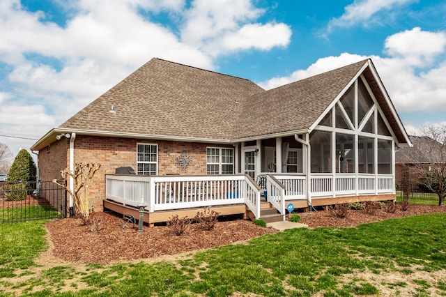 back of property with a sunroom, a lawn, a shingled roof, and fence