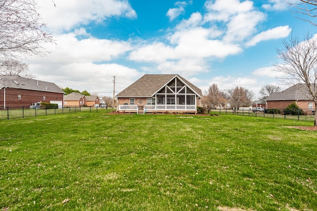 rear view of property featuring a lawn, a shingled roof, a fenced backyard, and a sunroom