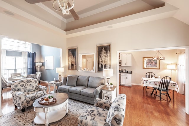 living room with crown molding, ceiling fan, baseboards, a towering ceiling, and wood finished floors