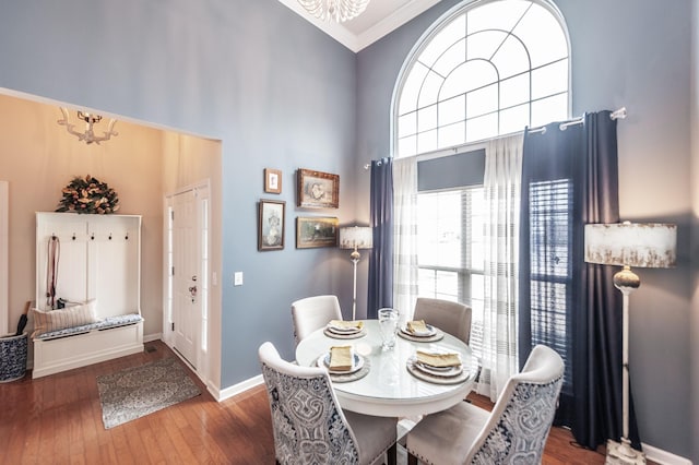 dining room featuring high vaulted ceiling, ornamental molding, hardwood / wood-style floors, baseboards, and a chandelier