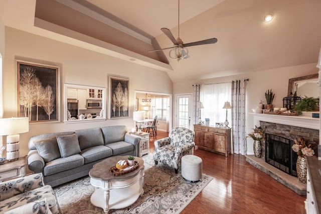 living area featuring wood finished floors, high vaulted ceiling, a fireplace, and ceiling fan