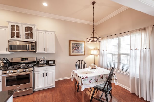 kitchen featuring ornamental molding, dark countertops, dark wood-style floors, appliances with stainless steel finishes, and white cabinets