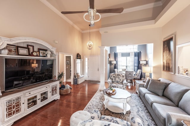 living room featuring a towering ceiling, wood finished floors, a ceiling fan, and ornamental molding