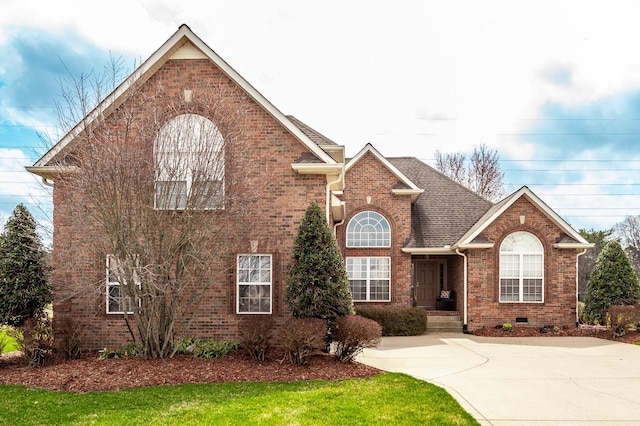 traditional home with crawl space, brick siding, and a shingled roof