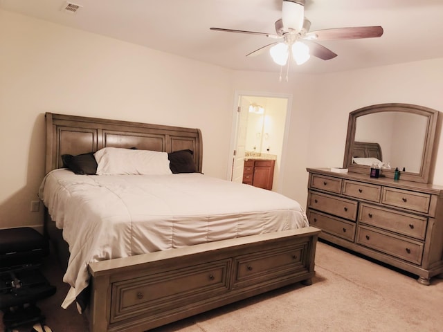 bedroom with visible vents, light carpet, ensuite bathroom, and a ceiling fan