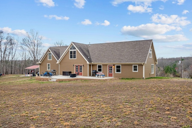 rear view of house featuring a yard, a patio, and roof with shingles