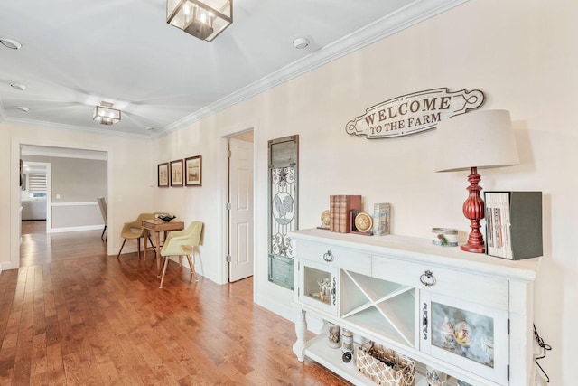corridor with crown molding, wood finished floors, and baseboards
