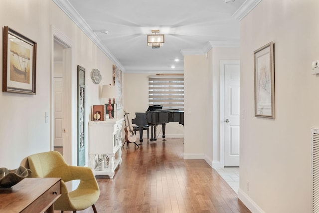 hall featuring light wood finished floors, baseboards, and ornamental molding
