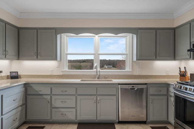 kitchen with gray cabinetry, crown molding, stainless steel appliances, wall chimney exhaust hood, and a sink
