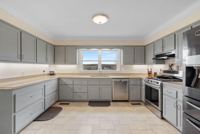 kitchen with gray cabinets, under cabinet range hood, a sink, stainless steel appliances, and crown molding