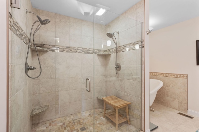 full bath with visible vents, a shower stall, tile walls, and a freestanding tub