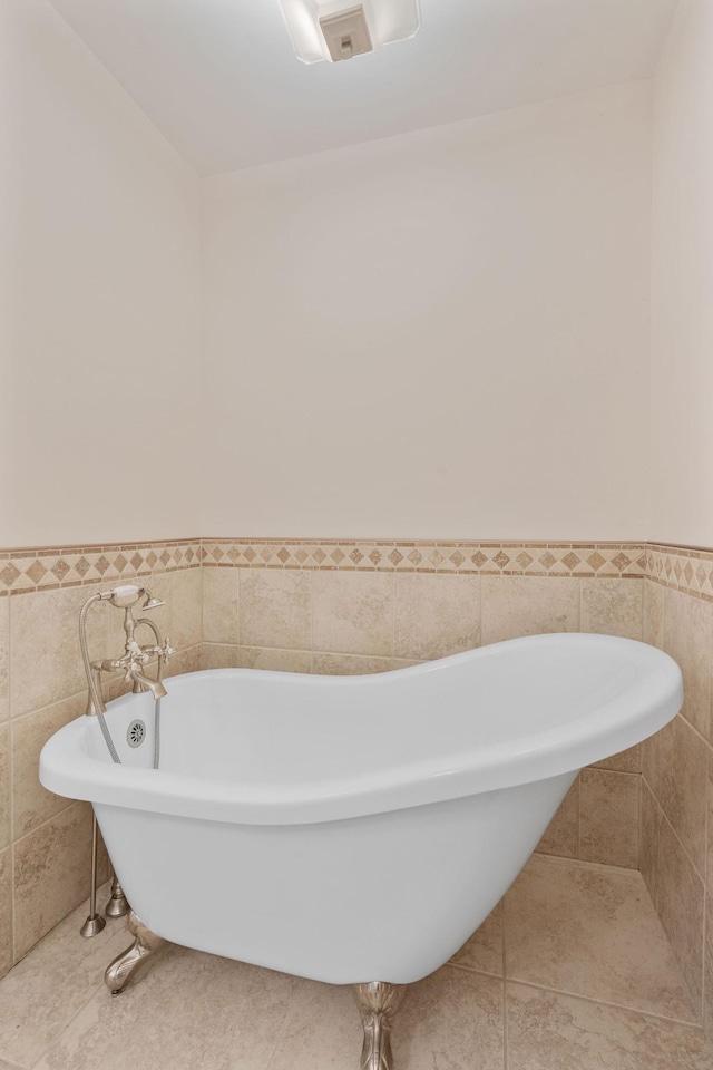 bathroom with a freestanding tub, tile walls, and a wainscoted wall