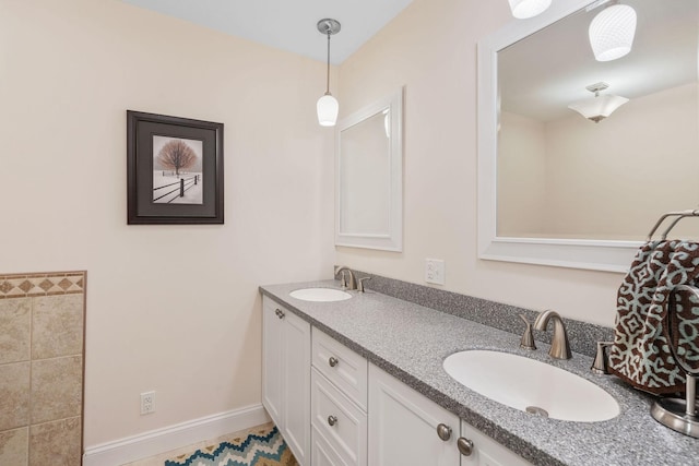 bathroom featuring a sink, baseboards, and double vanity