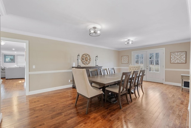 dining area with hardwood / wood-style floors, baseboards, and ornamental molding