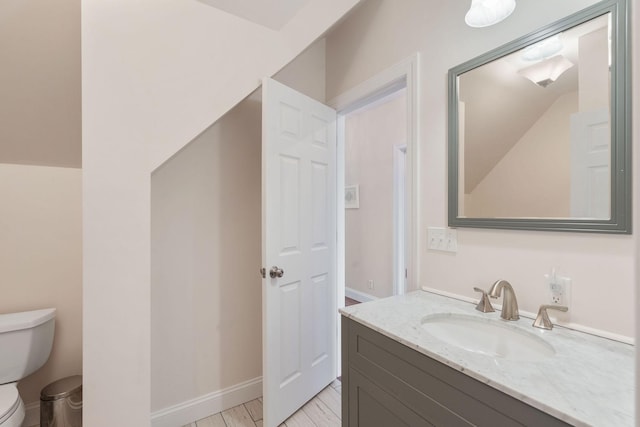 bathroom featuring vanity, toilet, and baseboards