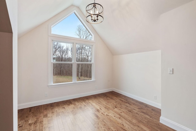 bonus room with an inviting chandelier, wood finished floors, baseboards, and lofted ceiling