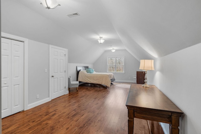 bedroom with lofted ceiling, wood finished floors, visible vents, and baseboards