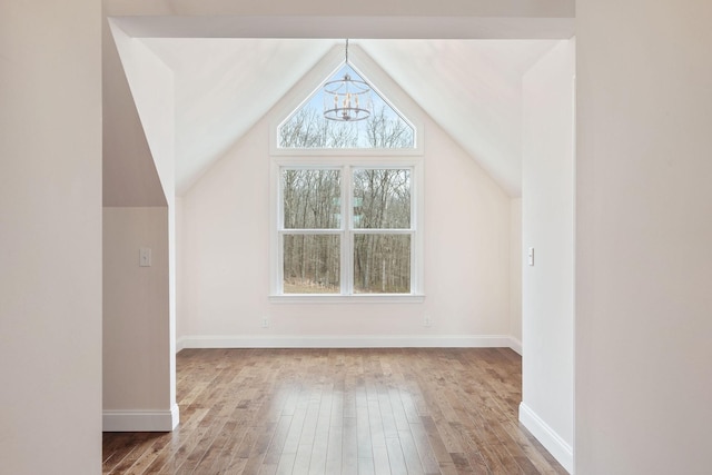 bonus room with vaulted ceiling, baseboards, an inviting chandelier, and wood finished floors