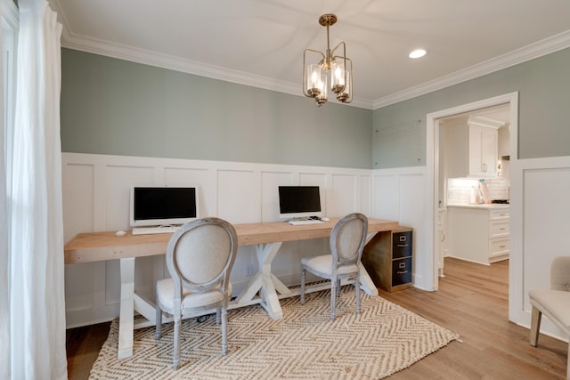 home office featuring a chandelier, light wood-type flooring, ornamental molding, wainscoting, and a decorative wall