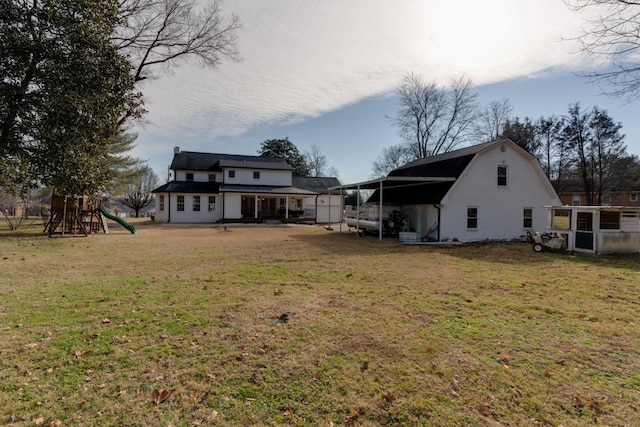 rear view of property featuring a gambrel roof, a lawn, and a playground