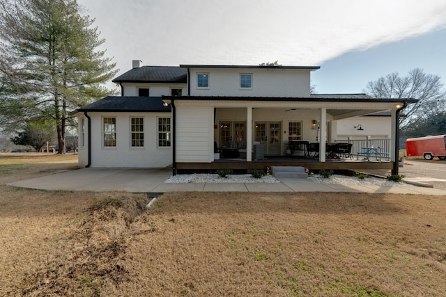 back of house featuring a lawn, french doors, and a chimney