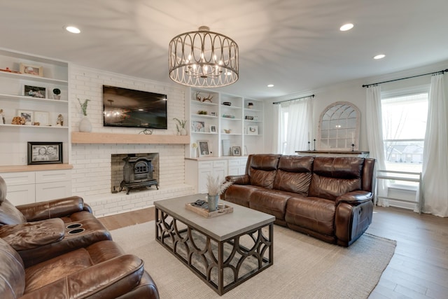 living room featuring built in shelves, a wood stove, recessed lighting, a notable chandelier, and light wood-type flooring