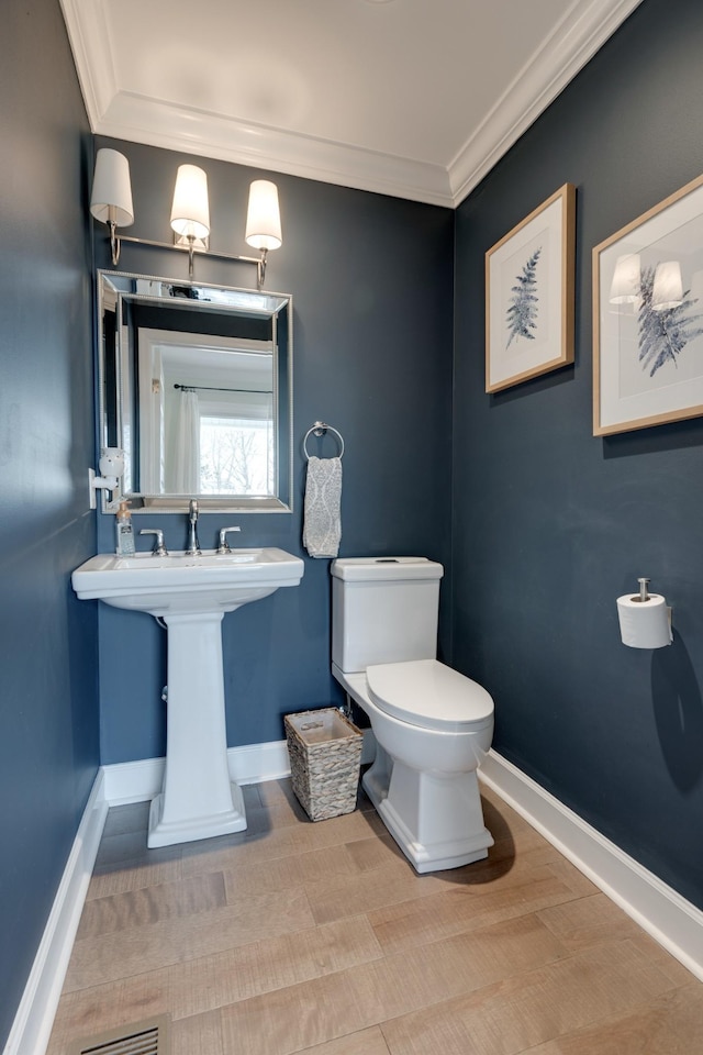 bathroom with baseboards, toilet, and crown molding