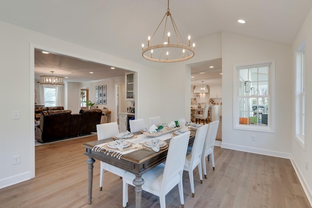 dining space featuring baseboards, lofted ceiling, recessed lighting, light wood-style floors, and a chandelier