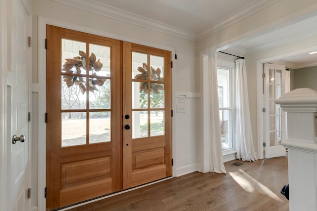 doorway to outside with visible vents, ornamental molding, and wood finished floors