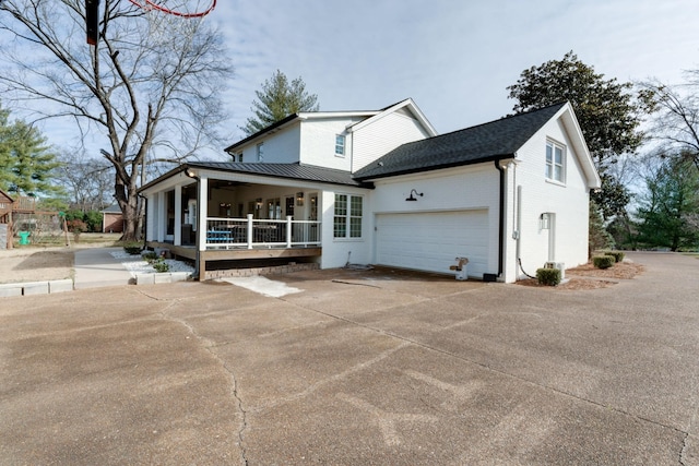 view of front of house with concrete driveway, an attached garage, brick siding, and covered porch