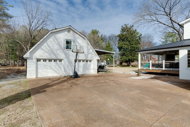 view of side of property with a garage, an outbuilding, concrete driveway, and a gambrel roof