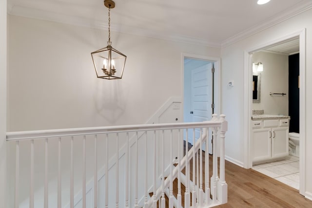 hall featuring crown molding, baseboards, an upstairs landing, an inviting chandelier, and light wood-style floors
