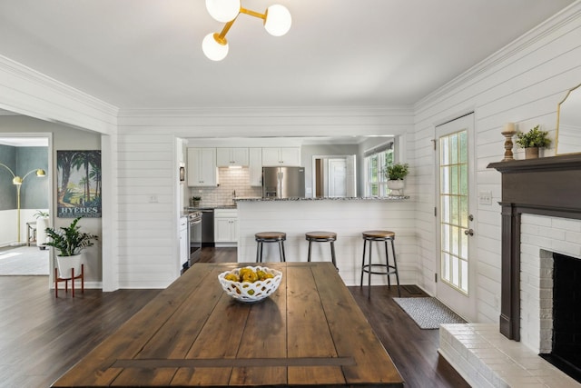 dining area featuring a fireplace, dark wood-style flooring, and ornamental molding