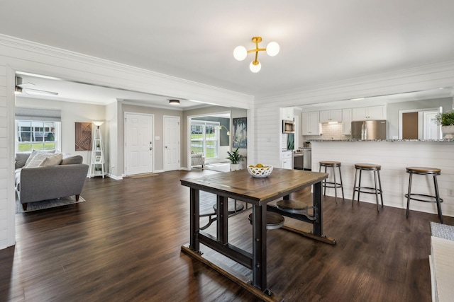 dining area featuring dark wood finished floors, crown molding, and a wealth of natural light