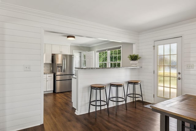 kitchen featuring light stone counters, white cabinets, a kitchen breakfast bar, and stainless steel fridge with ice dispenser