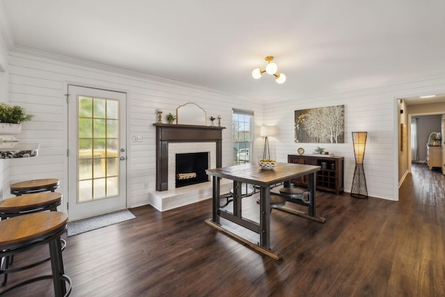 dining room with a brick fireplace, wood finished floors, crown molding, and an inviting chandelier