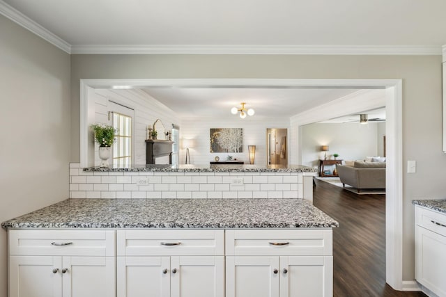 kitchen featuring backsplash, light stone countertops, open floor plan, a peninsula, and dark wood-style floors