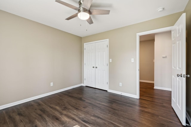 unfurnished bedroom with a closet, baseboards, a ceiling fan, and dark wood-style flooring