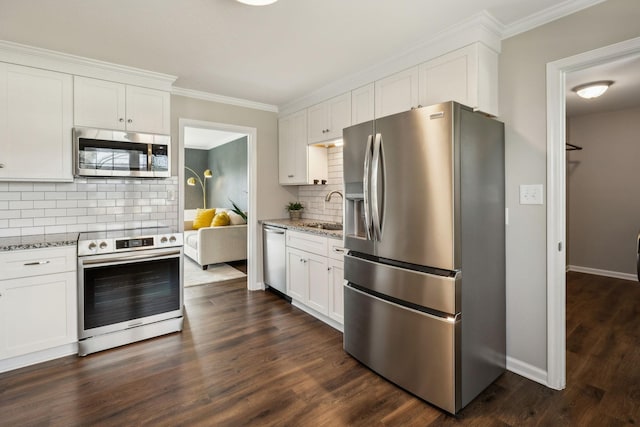 kitchen featuring dark wood finished floors, light stone counters, stainless steel appliances, white cabinetry, and a sink