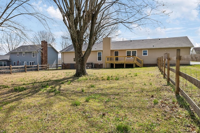 rear view of house featuring a fenced backyard, a lawn, and a deck