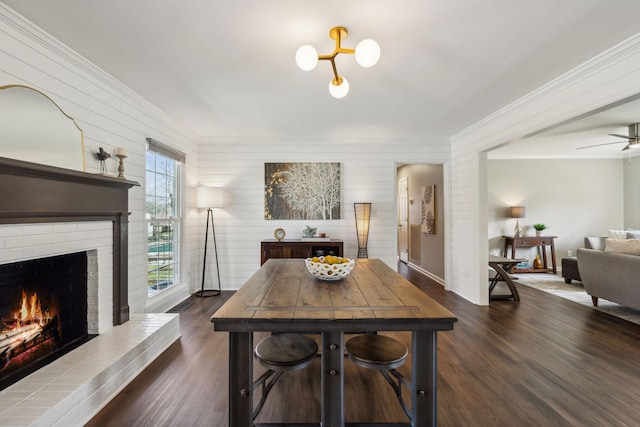 dining room with dark wood-type flooring, a brick fireplace, and ornamental molding