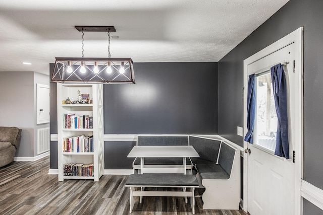 dining area with visible vents, a textured ceiling, baseboards, and wood finished floors