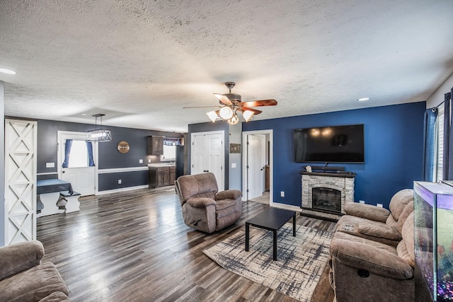 living area with a wealth of natural light, a fireplace, ceiling fan, and wood finished floors