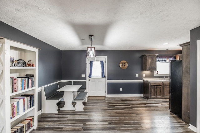 dining area featuring built in shelves, dark wood-style floors, baseboards, and a textured ceiling