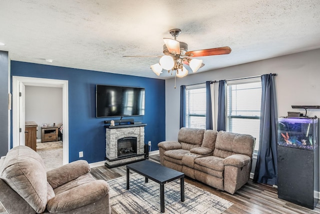 living area with baseboards, a textured ceiling, wood finished floors, and a ceiling fan