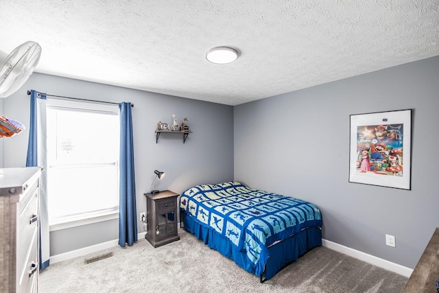 bedroom featuring visible vents, light carpet, a textured ceiling, and baseboards