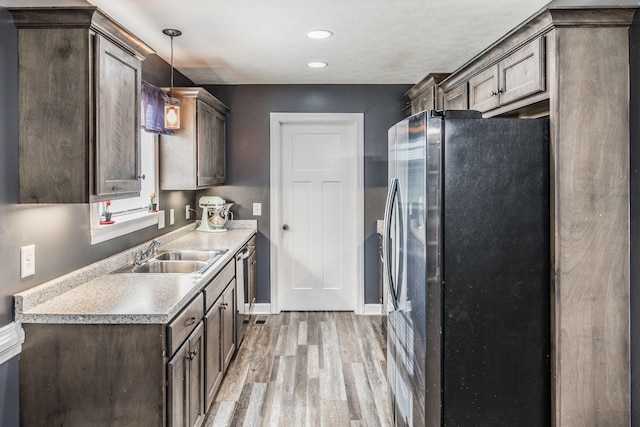 kitchen with light wood finished floors, a sink, stainless steel fridge with ice dispenser, light countertops, and dark brown cabinets