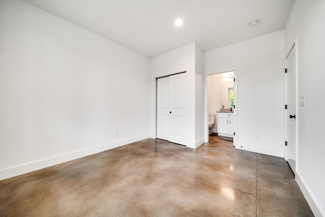 unfurnished bedroom featuring baseboards, recessed lighting, finished concrete floors, a closet, and ensuite bathroom