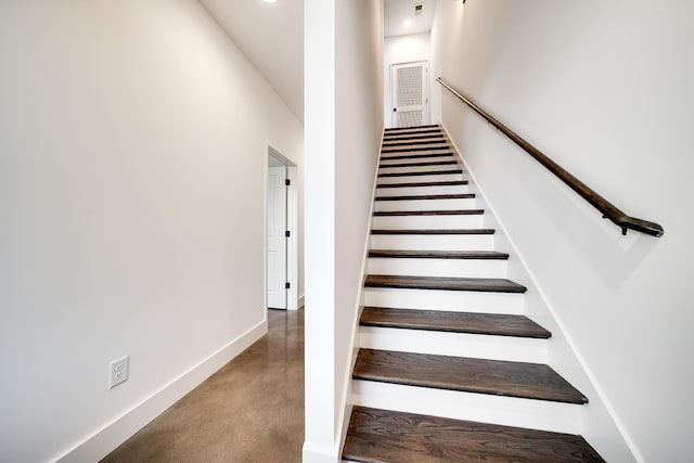 stairs featuring baseboards and concrete flooring