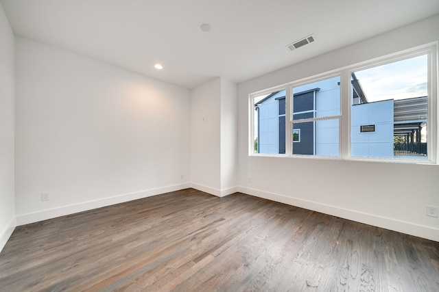 unfurnished room featuring wood finished floors, baseboards, and visible vents